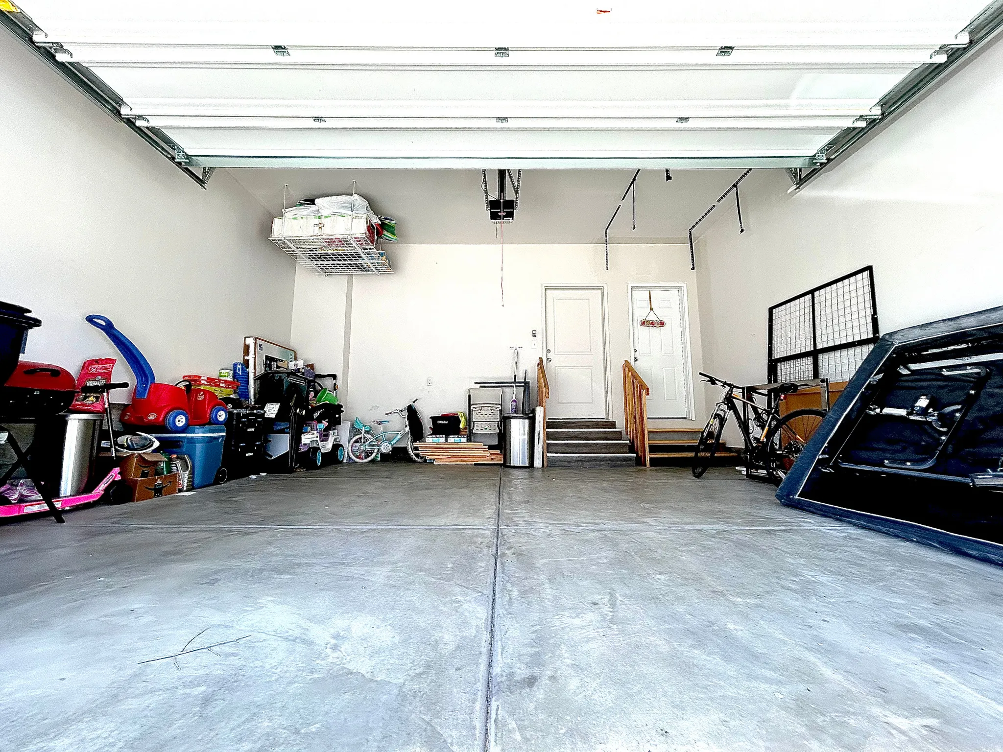 Attached garage with concrete flooring, overhead garage door, and interior access doors