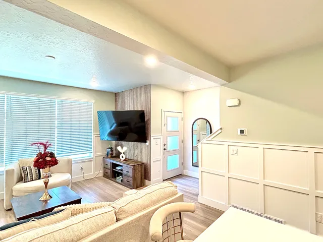 Recessed lighting, wood-finish flooring, accent wall paneling, white interior door with frosted glass panels, and board and batten wall details