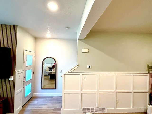 Wood-finish flooring, recessed lighting, white paneled wainscoting, and a multi-paneled door