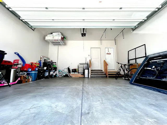 Attached garage with concrete flooring, overhead garage door, and interior access doors