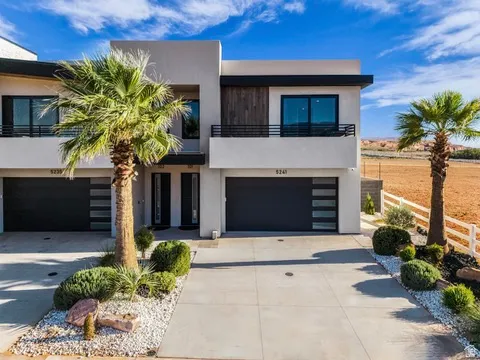 Modern exterior with stucco facade, a second-story balcony with metal railings, and an integrated garage with frosted glass panels