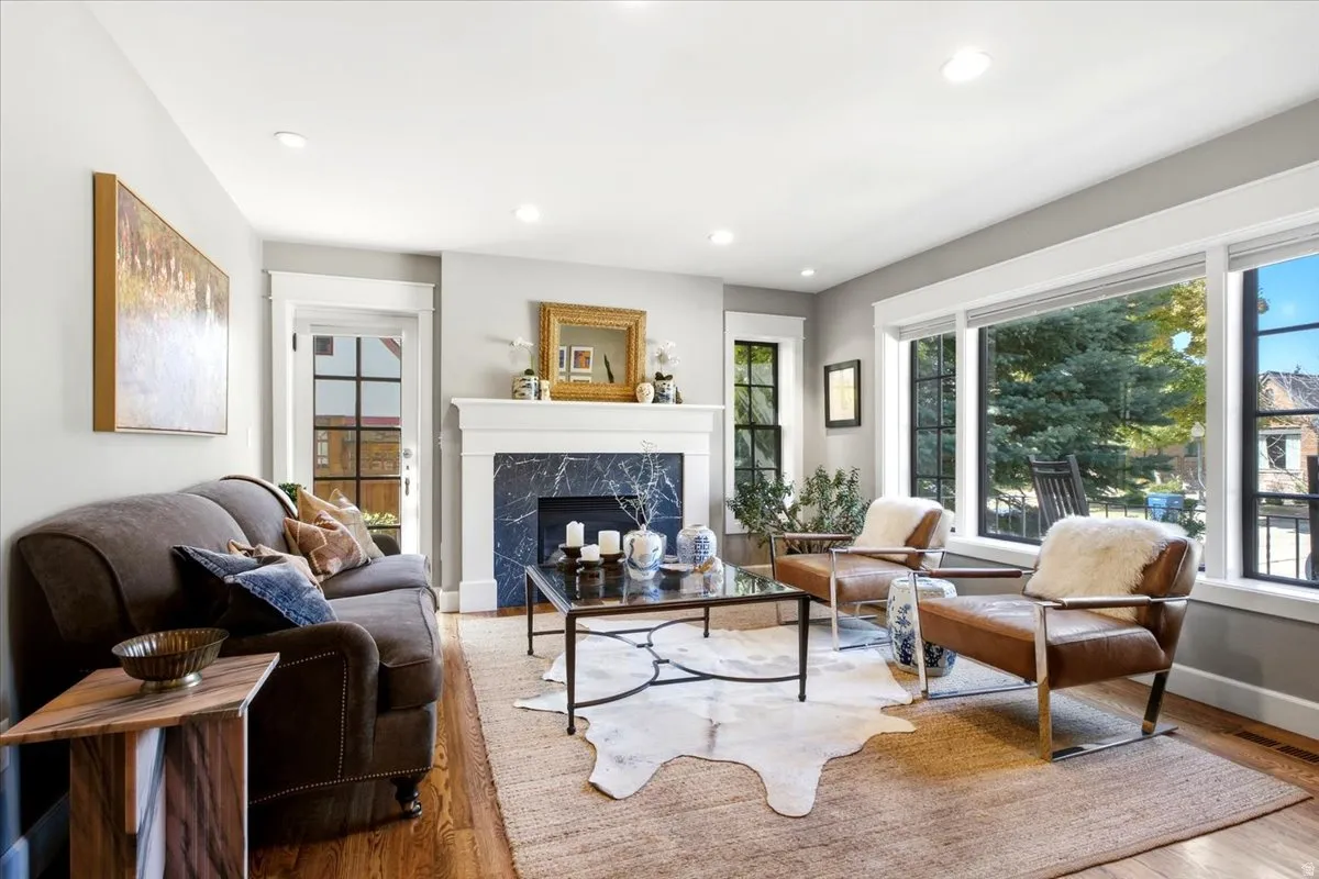 Hardwood flooring with a fireplace featuring a dark stone surround and white mantel
