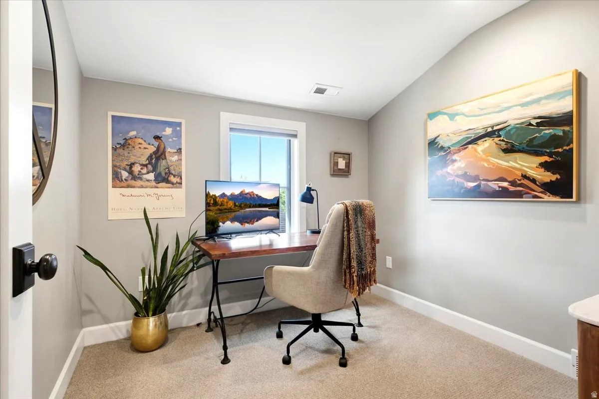 Carpeted room with a window, sloped ceiling, and a dark wood-finish desk