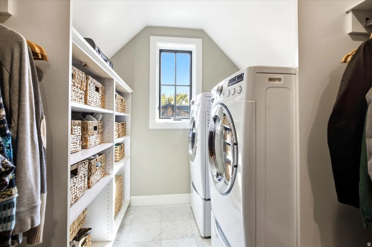 Integrated laundry appliances, built-in shelving, gridded window, attic ceiling, and light-toned wall paint