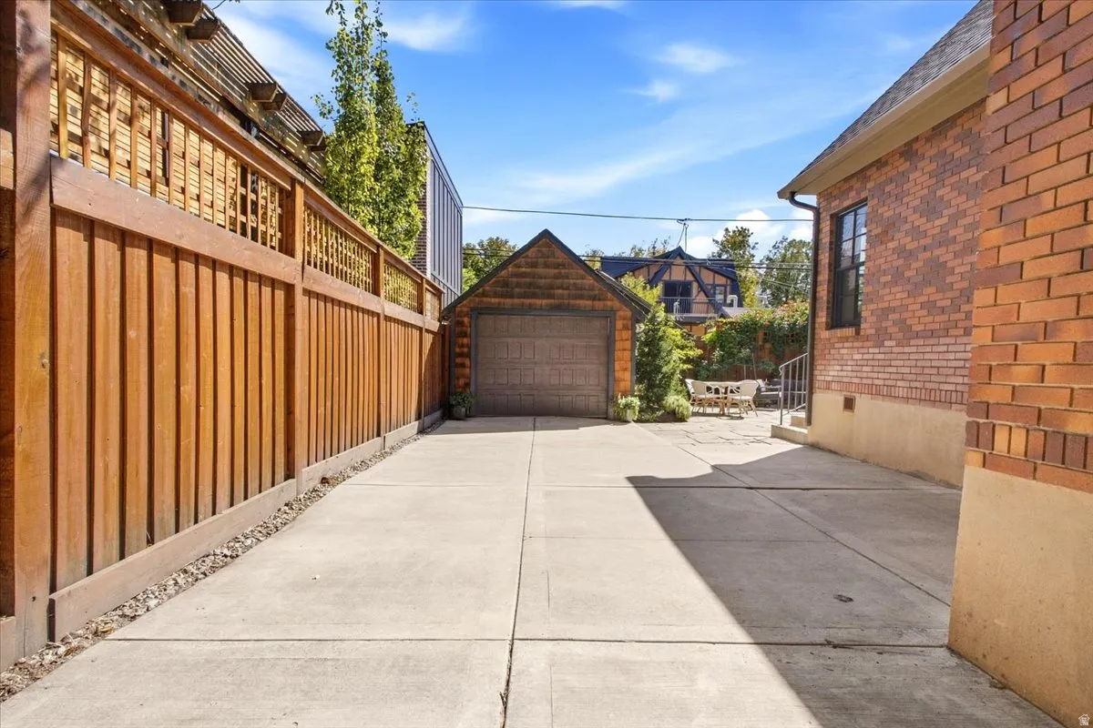 Paved driveway leading to a detached garage with wood-shake siding and an automatic door
