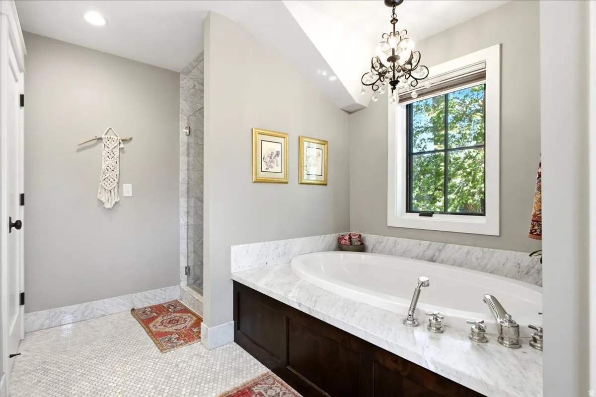 White mosaic tile flooring with a built-in soaking tub featuring a stone surround and dark wood cabinetry