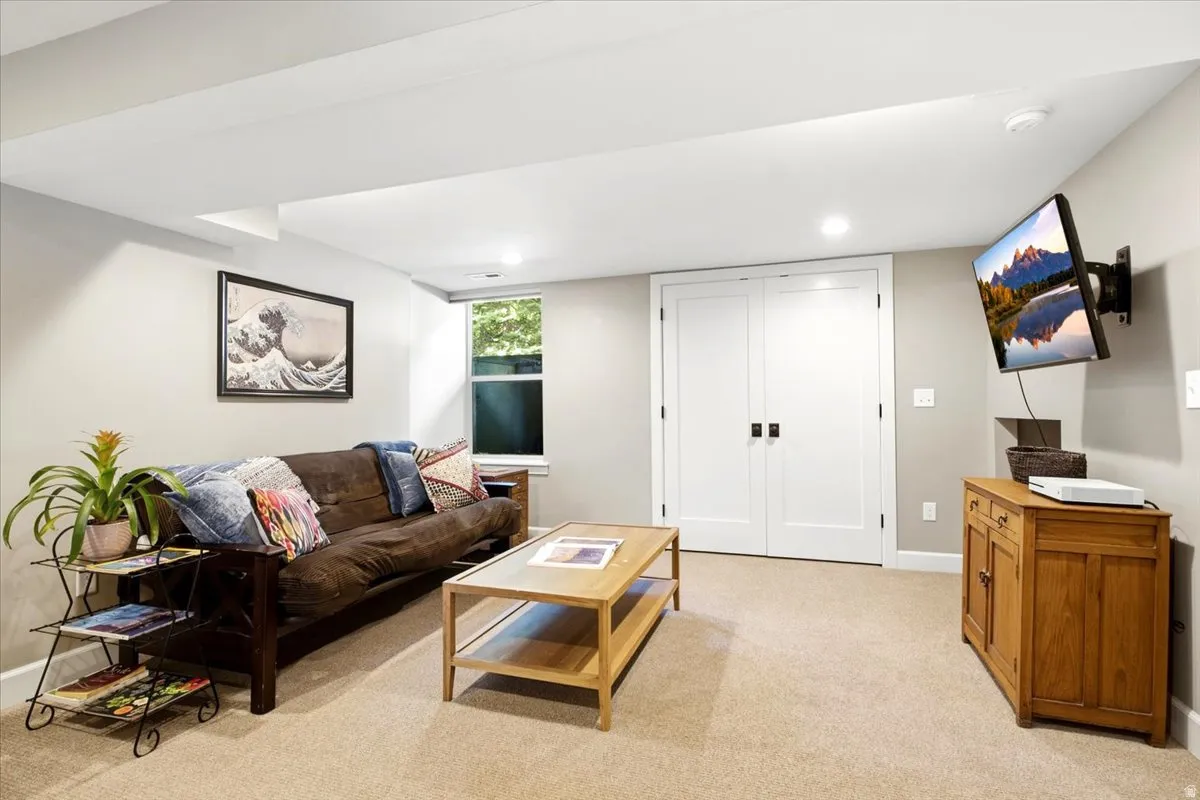 Recessed lighting illuminates the space, featuring neutral wall tones and plush carpet flooring