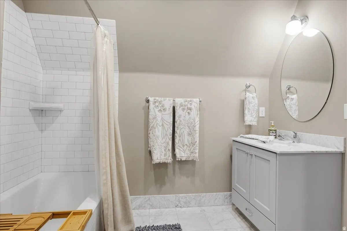 White subway tile bath surround, white bathtub, vanity with dual cabinet doors, integrated drawer, and a white countertop
