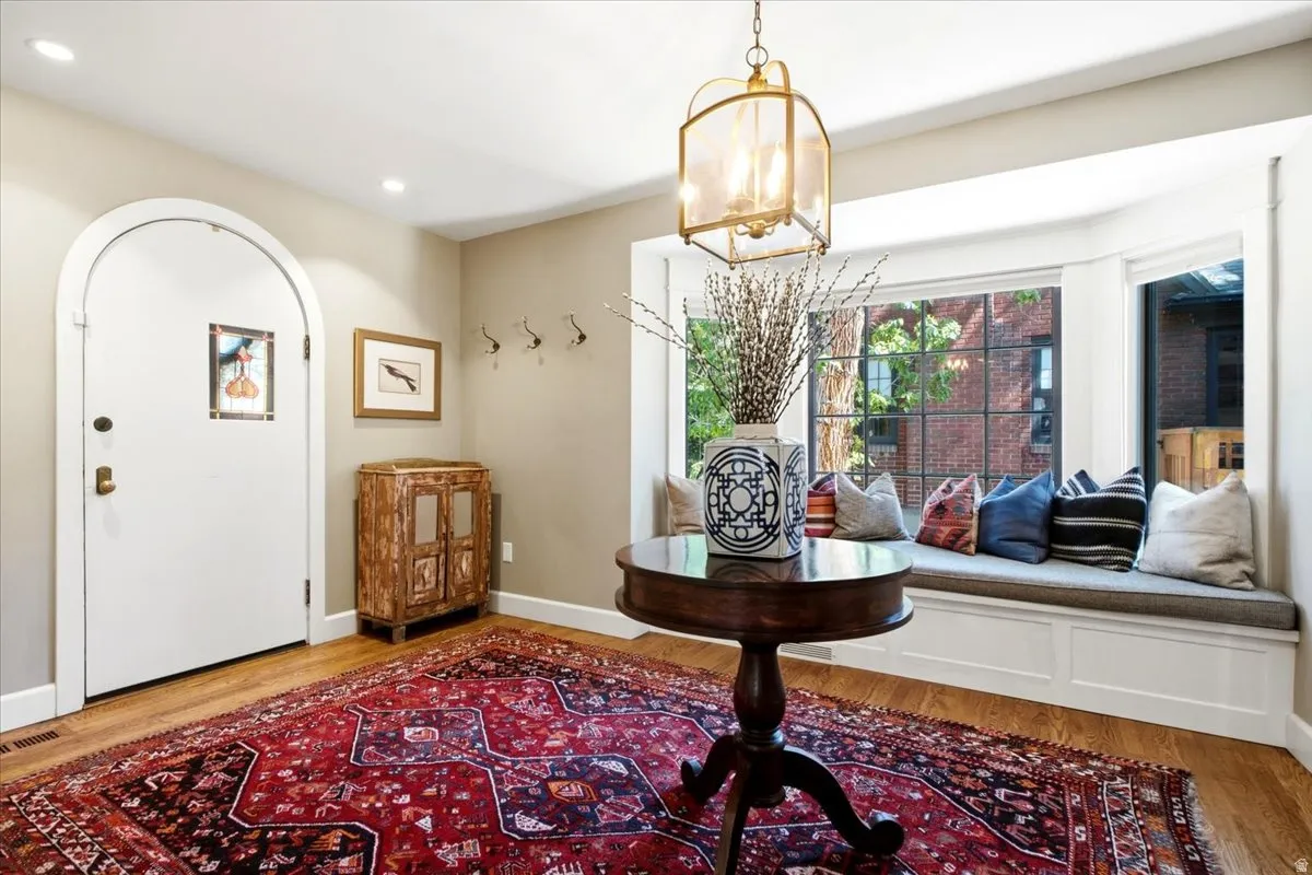 Hardwood flooring, arched doorway, recessed lighting, built-in window seating, and a brass-tone pendant light fixture