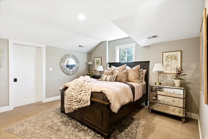 White interior door with dark hardware, recessed ceiling lighting, light neutral wall color, and a window providing natural illumination