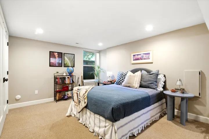 Recessed lighting, wall-to-wall carpeting, and a window with natural light