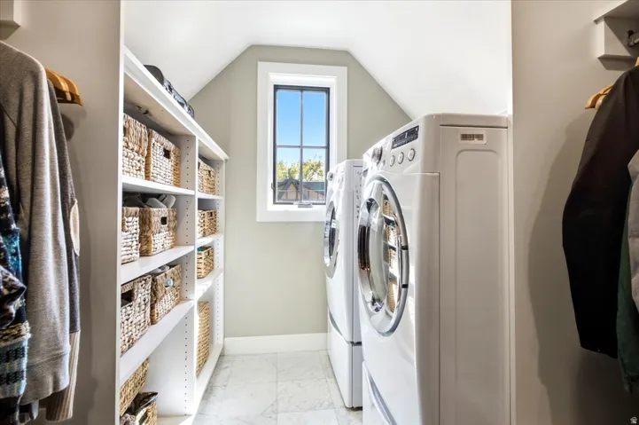 Integrated laundry appliances, built-in shelving, gridded window, attic ceiling, and light-toned wall paint