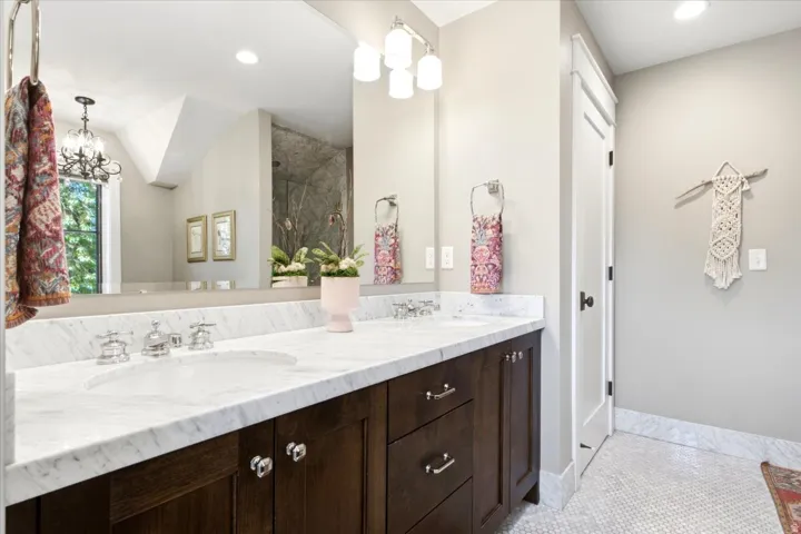 Dual vanity featuring a white marble countertop with undermount sinks, chrome fixtures, and dark wood-finish cabinetry
