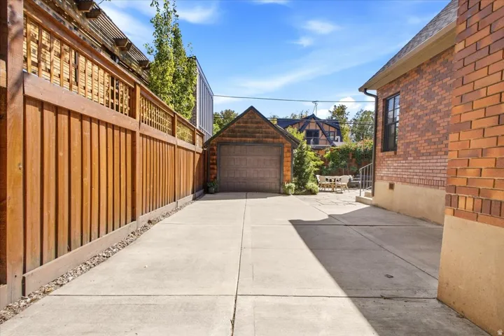 Paved driveway leading to a detached garage with wood-shake siding and an automatic door