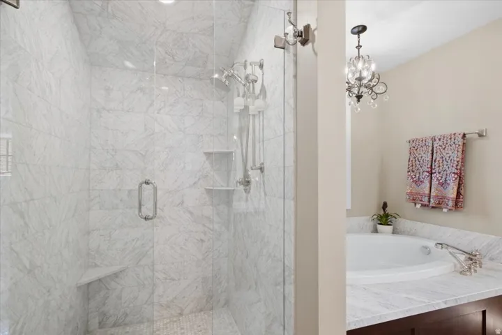 Spacious shower with glass enclosure, integrated shelving, and a built-in seat
