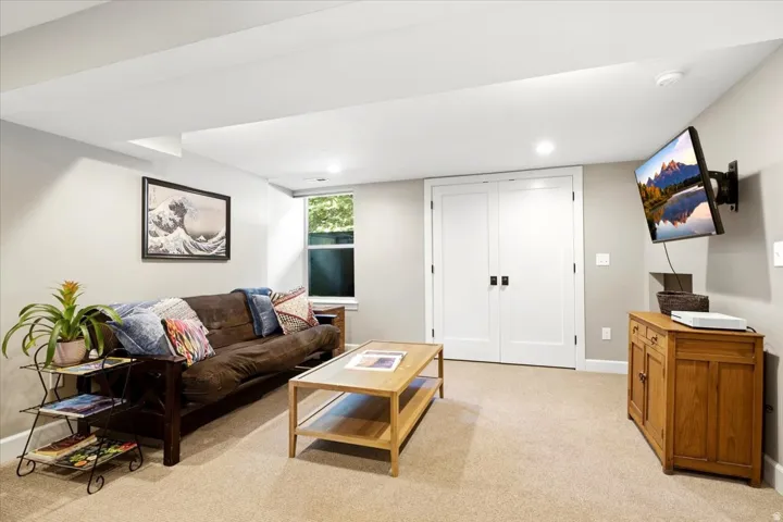 Recessed lighting illuminates the space, featuring neutral wall tones and plush carpet flooring