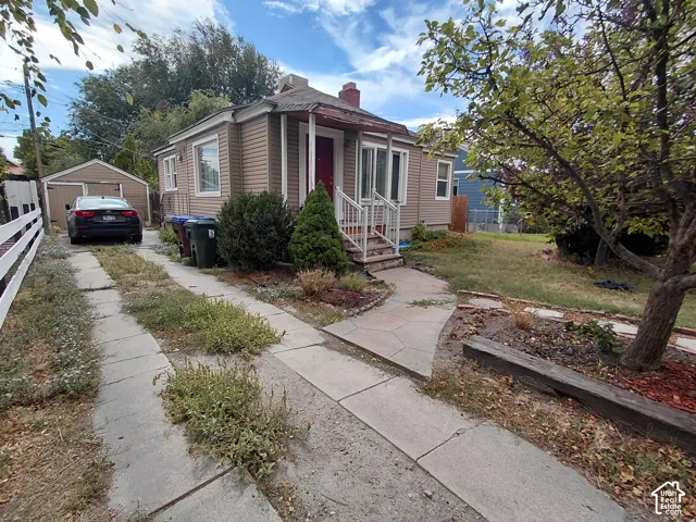 Siding exterior with a covered porch entry, concrete walkway, and a detached garage