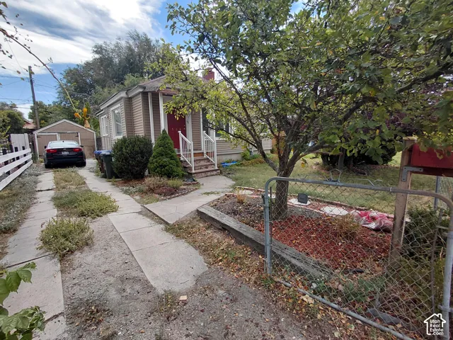 Siding exterior, covered porch, red entry door, detached garage, concrete driveway