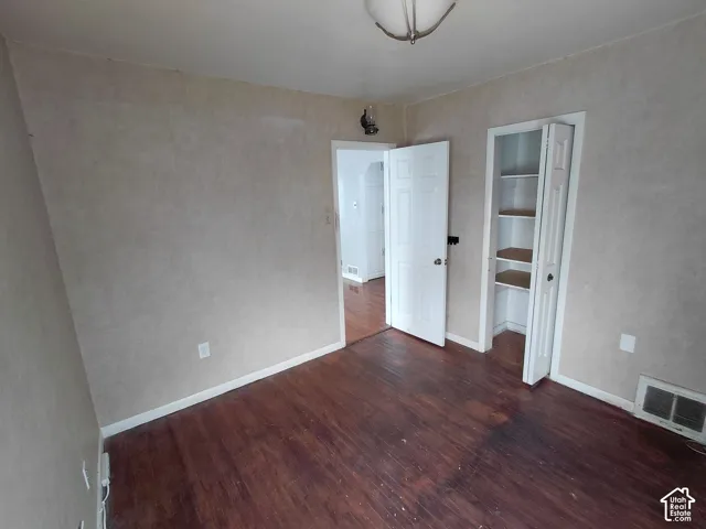 Dark wood-finish flooring with white trim, a closet with built-in shelving, and a semi-flush mount ceiling light