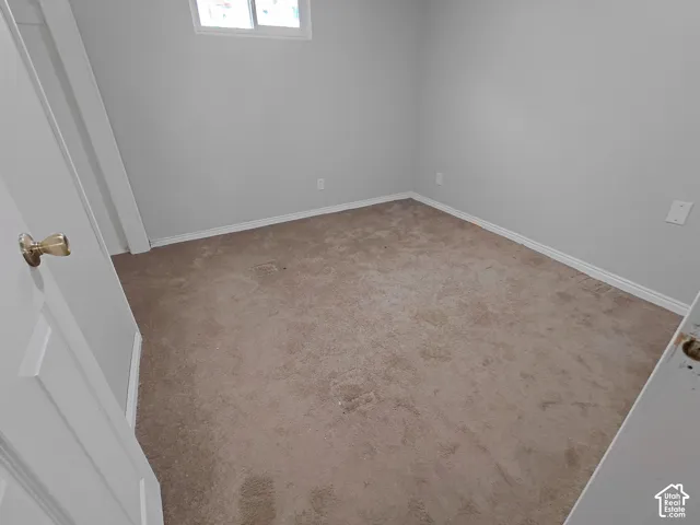 Neutral wall color with carpeted flooring, featuring a window and white trim