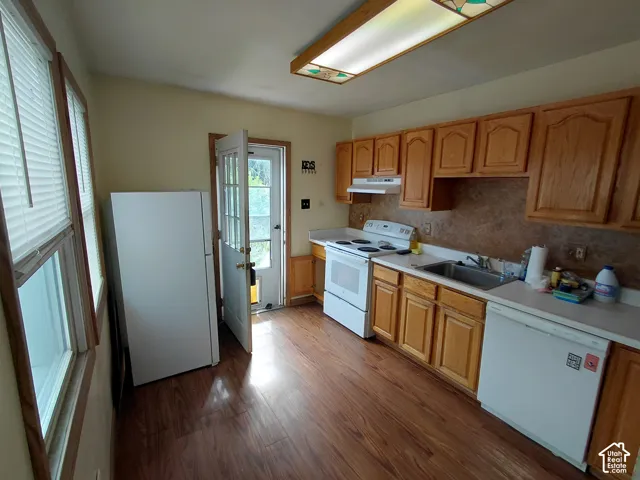 Kitchen with wood-finish flooring, wood cabinetry, and a full suite of white appliances
