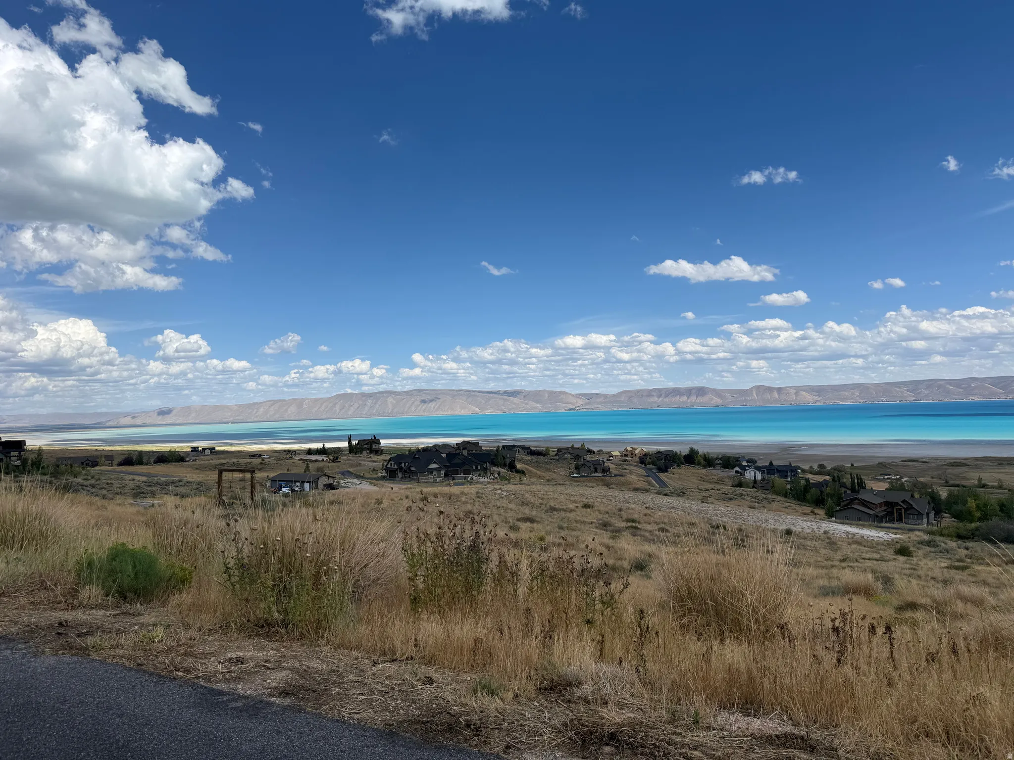 Expansive landscape featuring a large body of water, distant mountains, and scattered residential structures