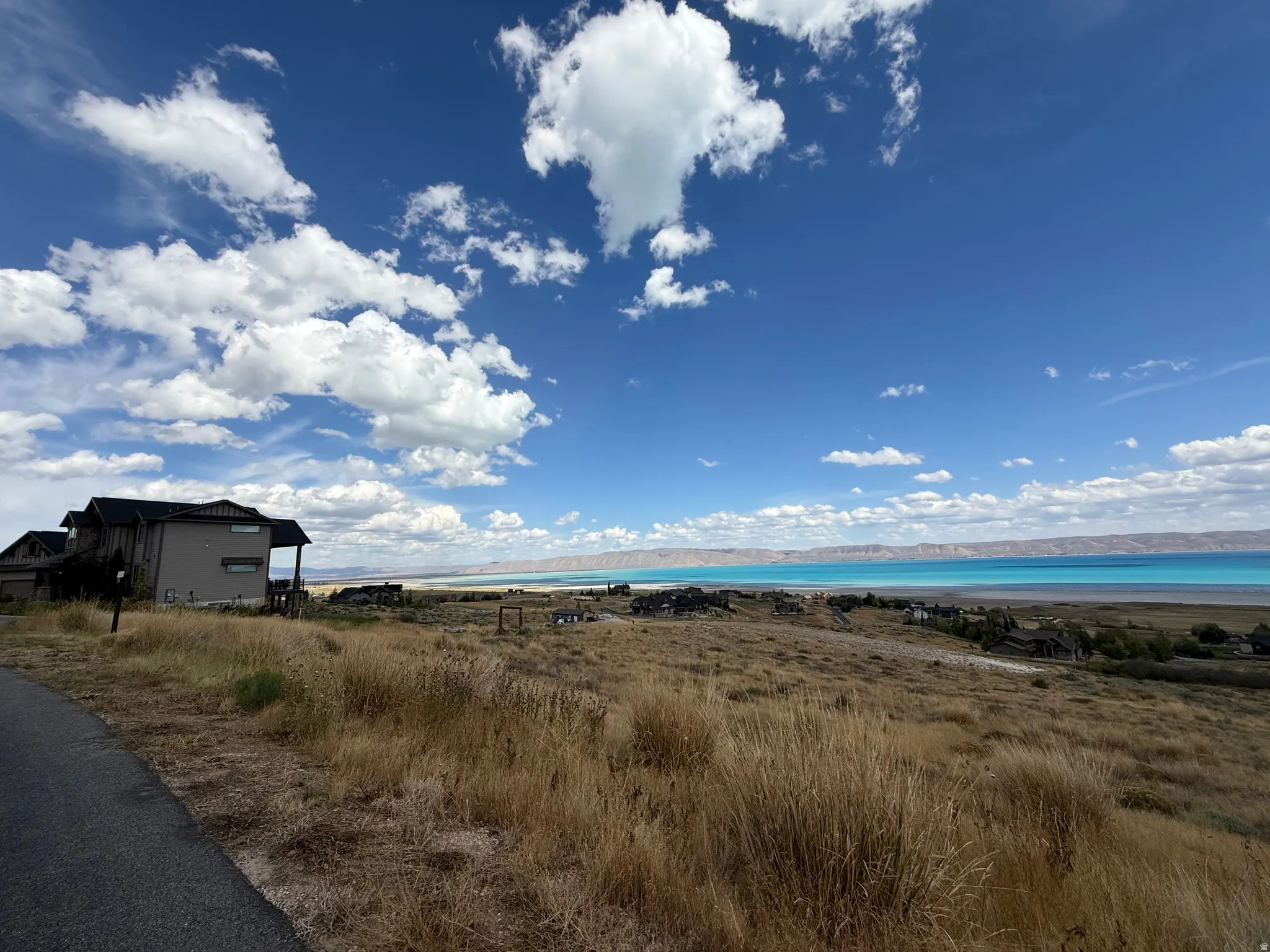 Property with expansive natural landscaping, hillside setting, and distant water feature