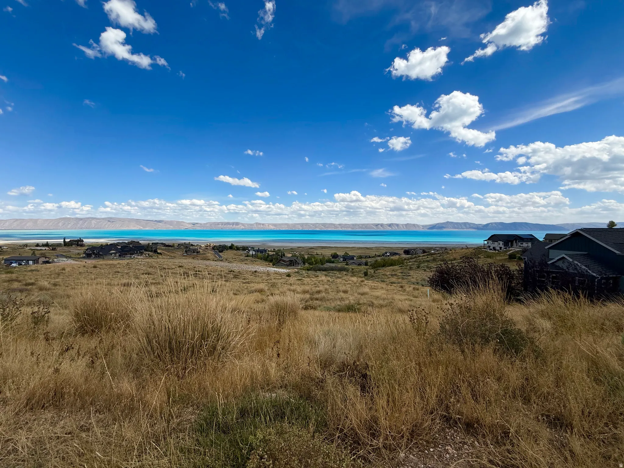 Expansive property with a distant water feature, rolling hills, and established residential structures