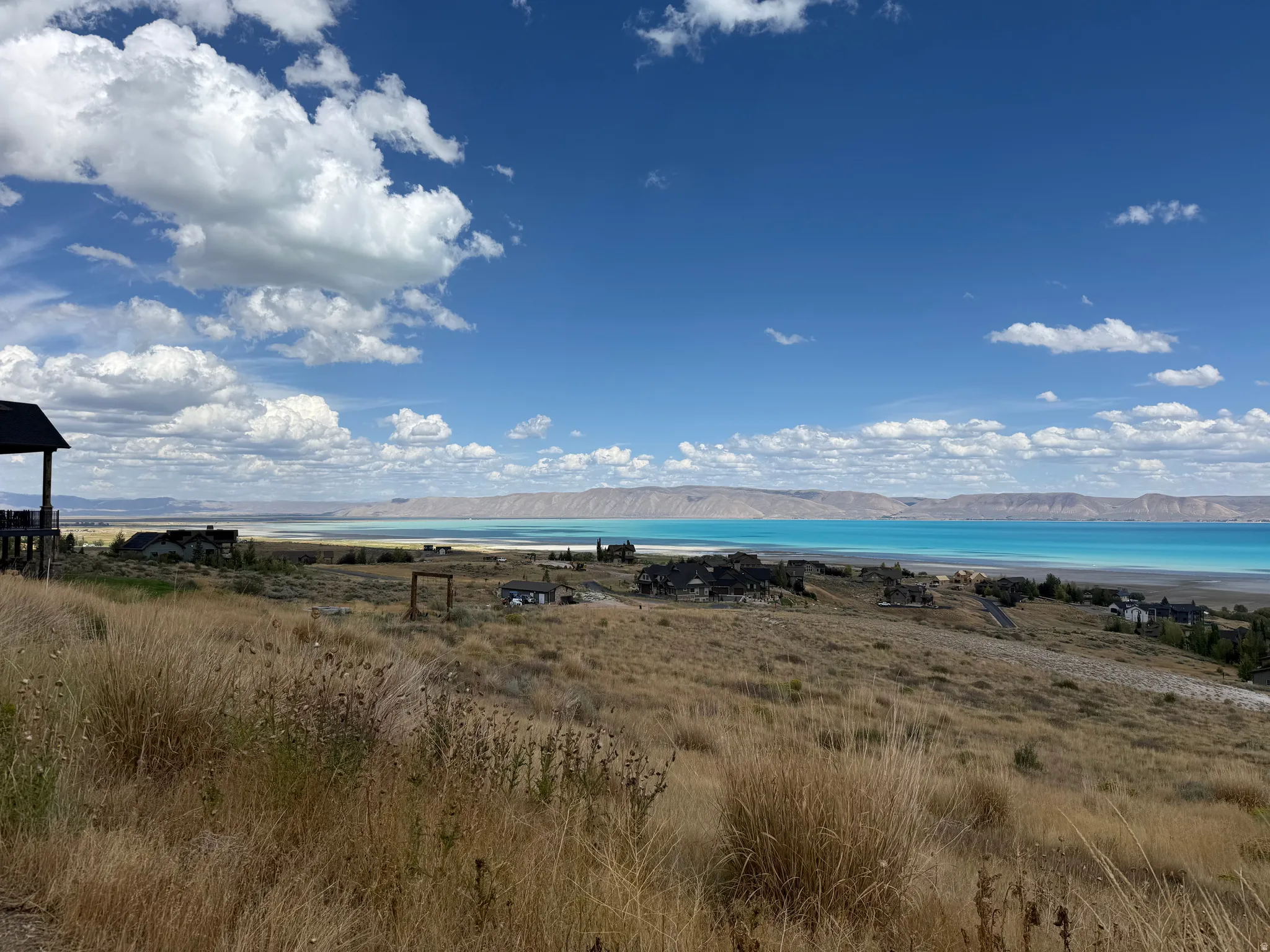 Expansive landscape featuring a large body of water, distant mountains, and scattered residential properties