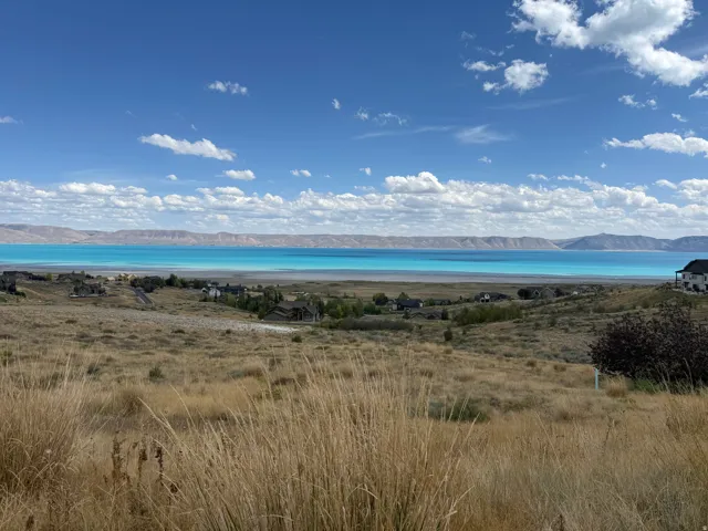 Expansive landscape with distant bodies of water, framed by a clear sky and mountains