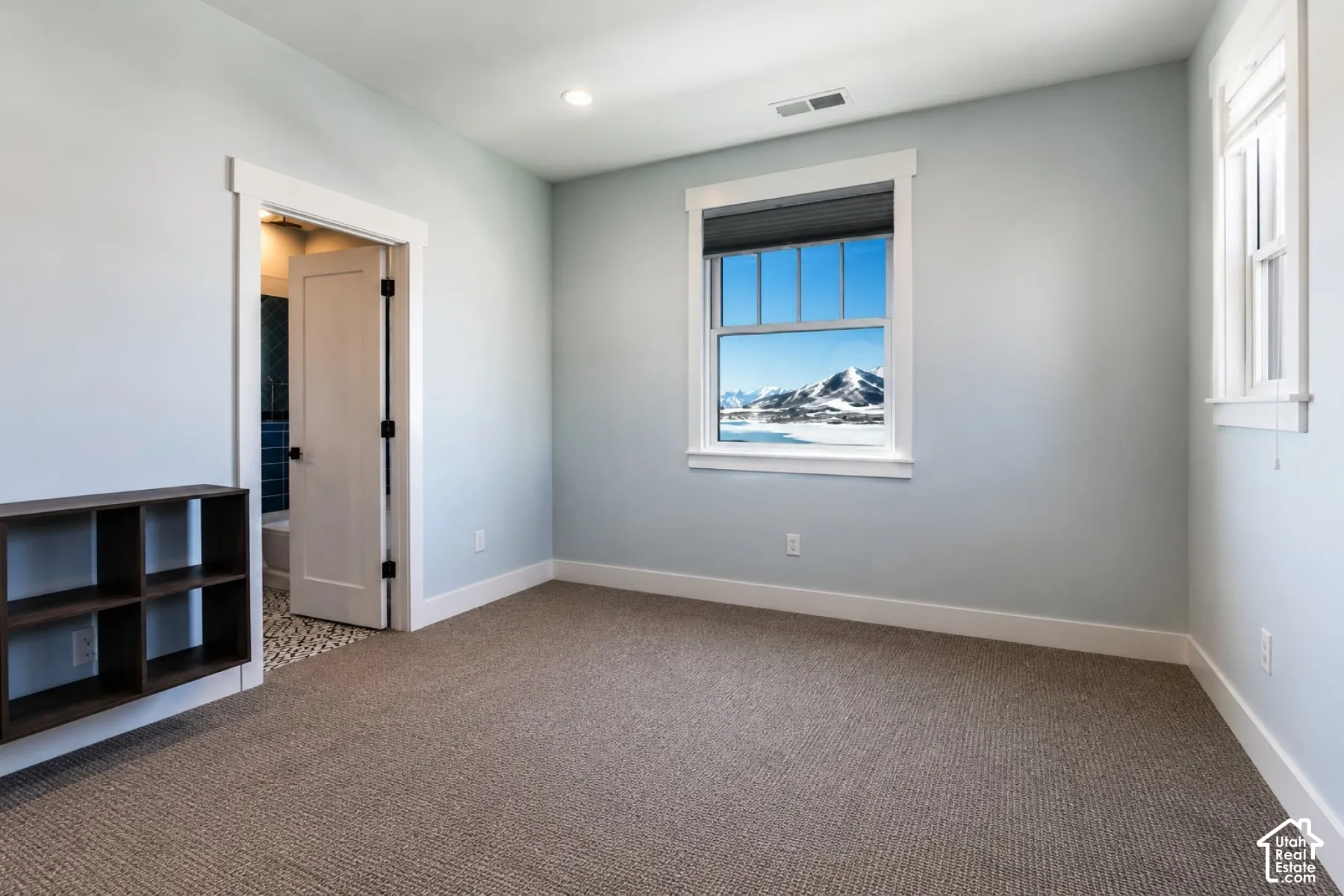 Wall-to-wall carpeting, multiple windows with white trim, and recessed lighting