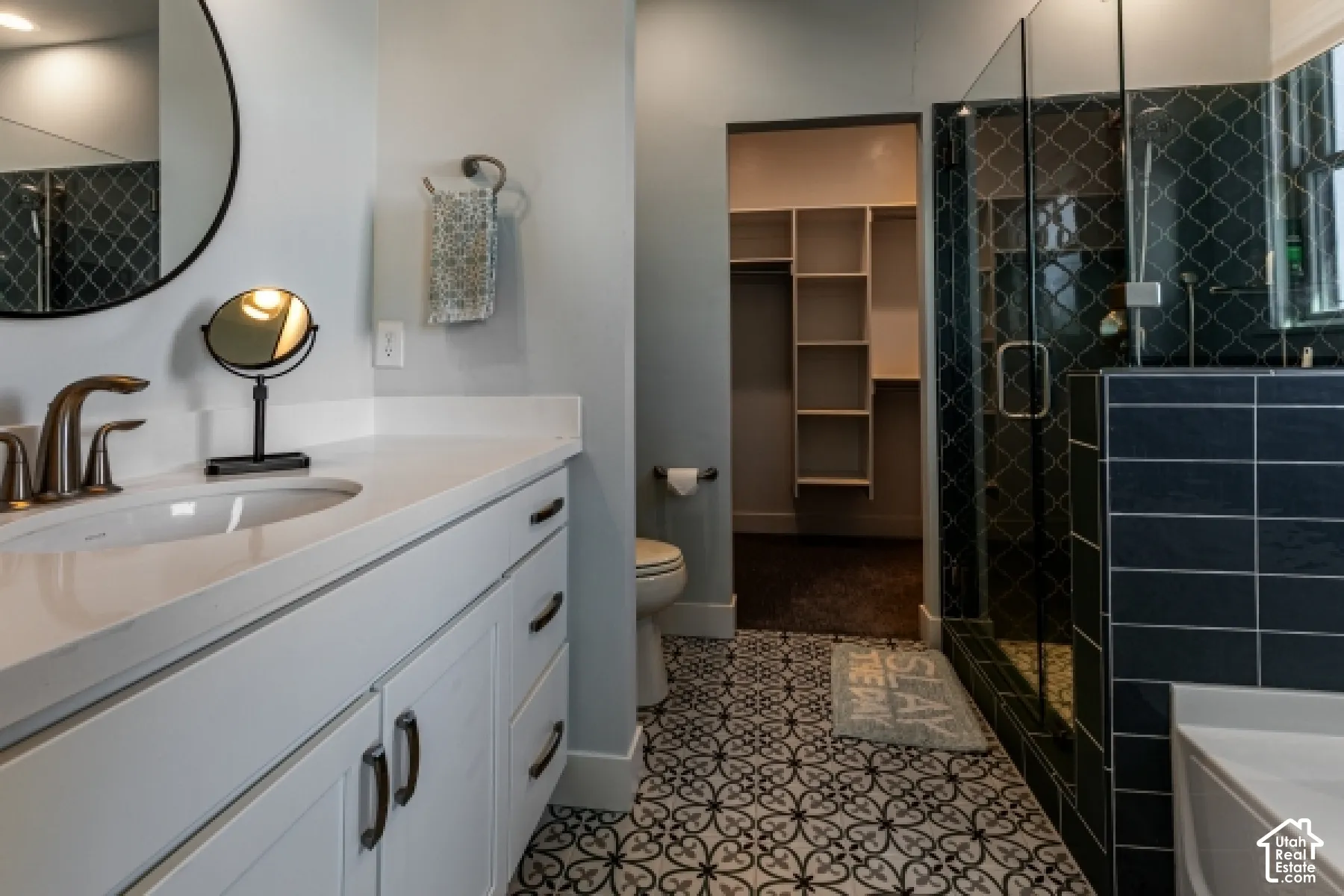 White shaker vanity with an undermount sink, a bronze-finish faucet, and a light-toned countertop