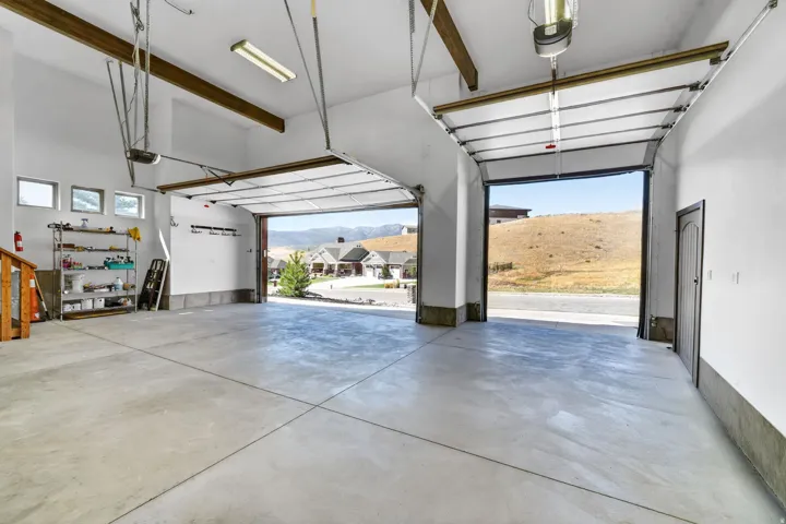 Spacious garage featuring a concrete floor, two overhead garage doors, and high ceilings with exposed beams