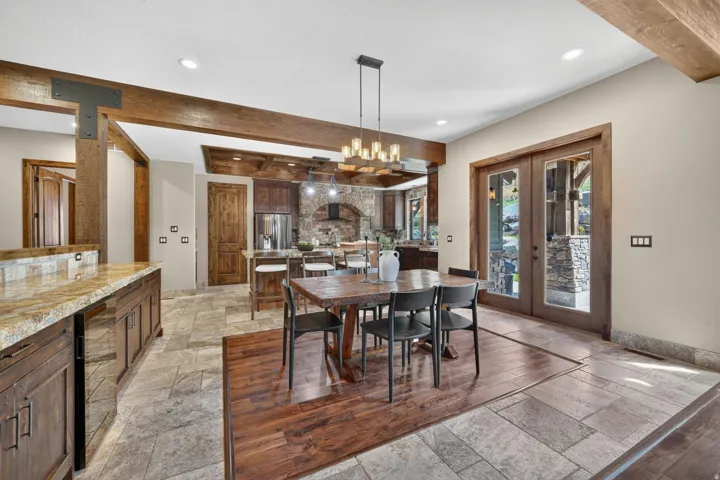 Exposed wood beams, stone tile flooring, French doors, wood-finish flooring, and a built-in bar with stone countertop