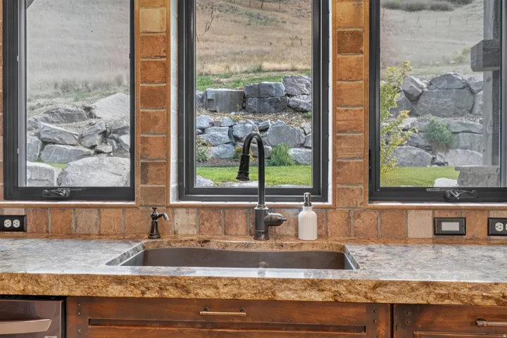 Integrated basin sink with an oil-rubbed bronze faucet, set within a stone countertop and tile backsplash