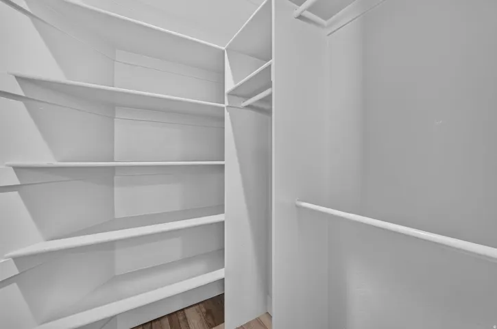 Built-in closet system with multiple shelving units, hanging rods, and wood-finish flooring