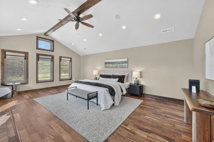 Vaulted ceiling with exposed wood beam, recessed lighting, wood-finish flooring, and multiple windows with wood trim