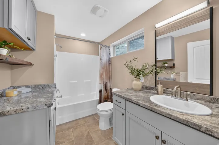 Bathroom featuring dual vanity areas with light gray cabinetry and patterned countertops
