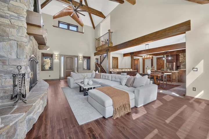 Stone fireplace, wood-finish flooring, exposed wood beams, vaulted ceiling, and dual entry doors
