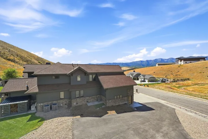 Multi-level residence with stone and siding exterior, sloped roofline, and attached storage structure