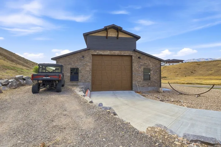 Stone facade building with a prominent brown garage door and an upper level featuring dark siding