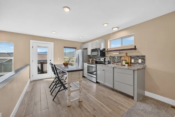 Kitchen area featuring wood-finish flooring, light-toned cabinetry, stainless steel appliances, and a tiled backsplash