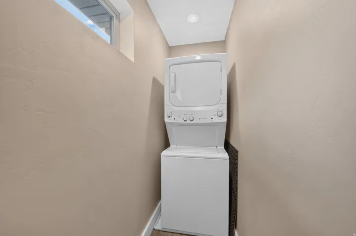 Stackable washer and dryer unit with a window providing natural illumination and recessed ceiling lighting