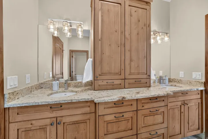 Dual vanity with stone-look countertops, integrated sinks, and wood cabinetry