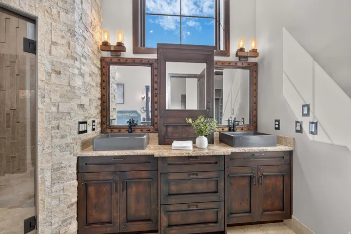 Dual vessel sinks set atop a stone countertop with custom wood cabinetry