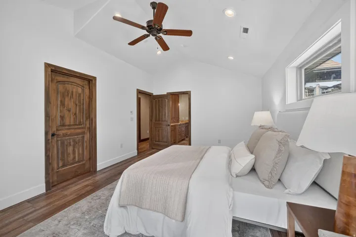 Vaulted ceiling with a ceiling fan, recessed lighting, wood-finish flooring, and wood-paneled doors