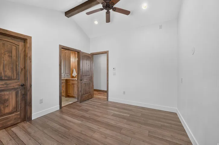 Vaulted ceiling with exposed wood beam, wood-finish flooring, recessed lighting, and a ceiling fan