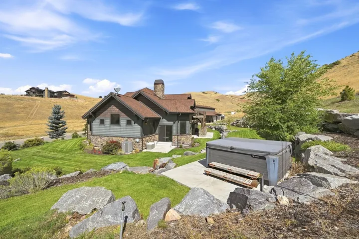 Exterior featuring stone and siding finishes, a prominent stone chimney, and a brown shingle roof