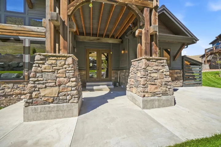 Stone veneer columns supporting a timber-framed entryway with a wood-plank ceiling