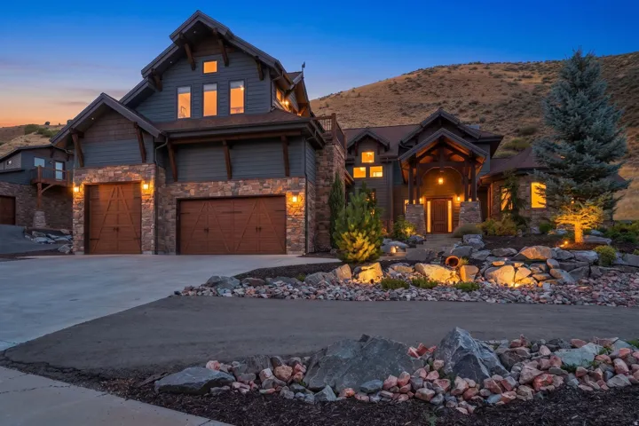 Stone and siding exterior with wood accents, multiple garage bays, and a covered entry